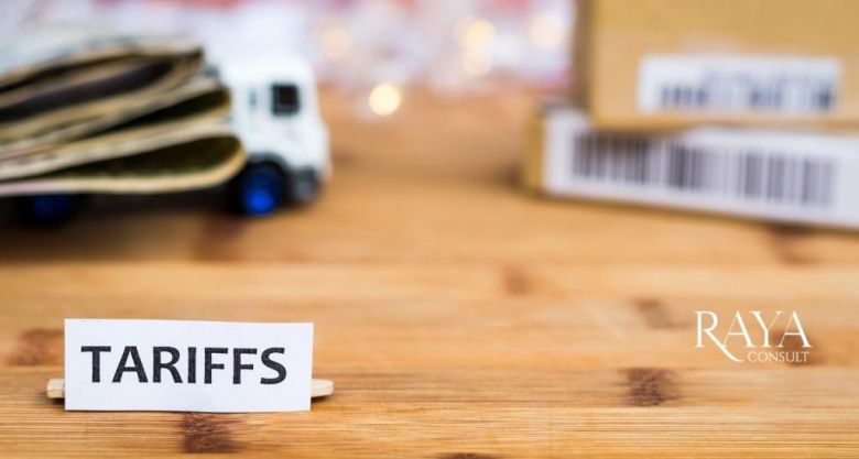 Imagem com o fundo desfocado, contendo um caminhão de brinquedo no canto superior esquerdo e duas caixas no canto superior direito e um papel branco à frente da imagem, no canto inferior esquerdo, focado, escrito "TARIFFS"